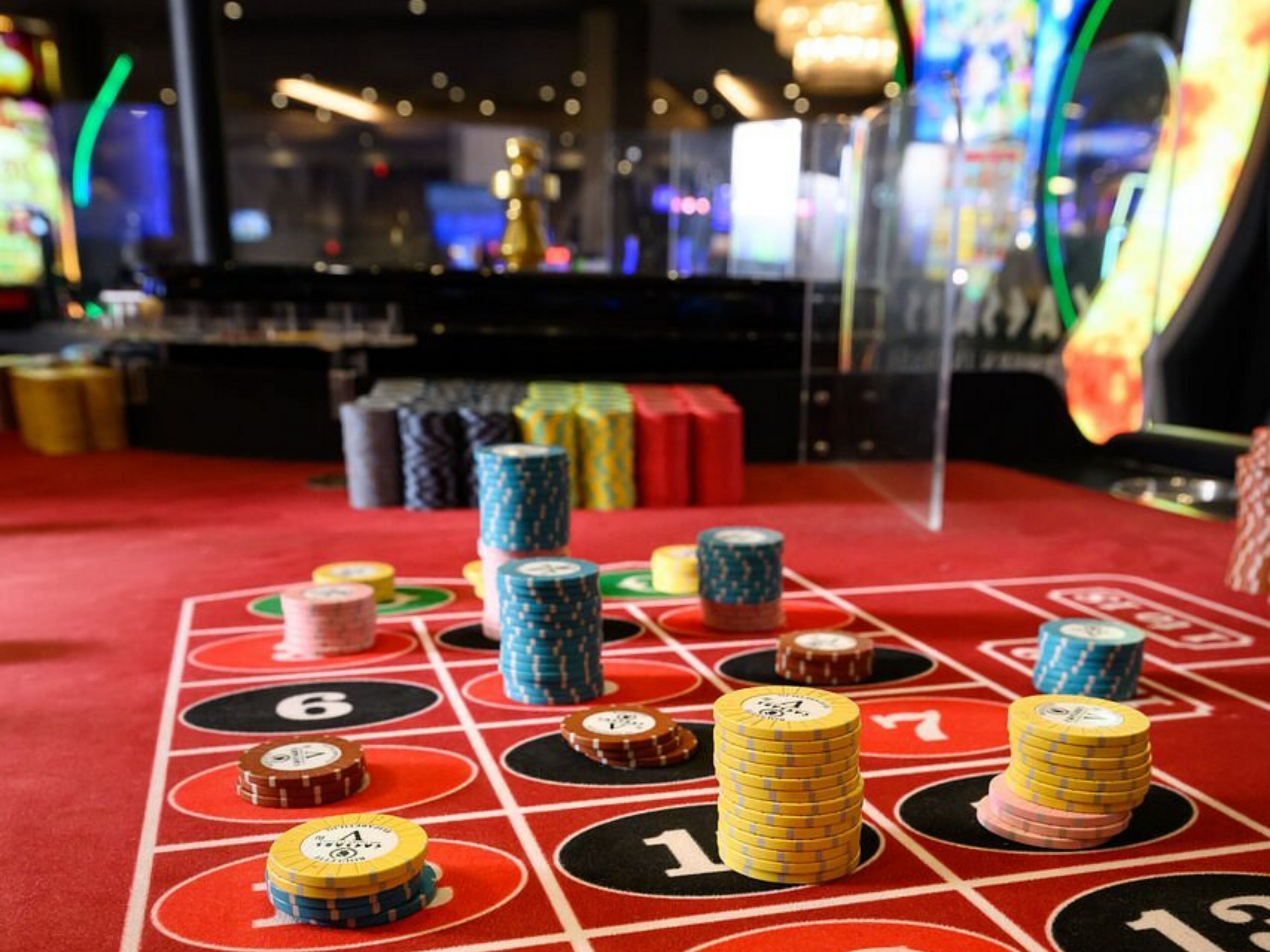 A craps table with stacks of chips and a roulette wheel.