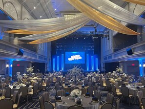 A banquet hall with round tables, chairs, and a stage with a 'HAPPY NEW YEAR' sign. - Caesars Southern Indiana - A Caesars Rewards Destination (Elizabeth)
