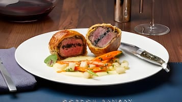 Ein Teller Essen mit einem Messer und einem Glas Rotwein auf einem Tisch.