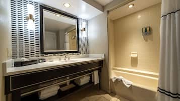 A modern bathroom with a dual sink vanity, a large mirror, a bathtub, and a shower area.