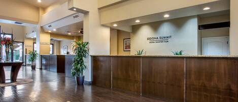 Zona de recepció d'hotel amb taulell de fusta, plantes en test i un cartell del Sedona Summit Hilton Vacation Club.