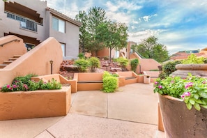 A courtyard with a central seating area, surrounded by planters with flowers, and a staircase leading to an upper level. - Hilton Vacation Club Sedona Summit (Sedona)