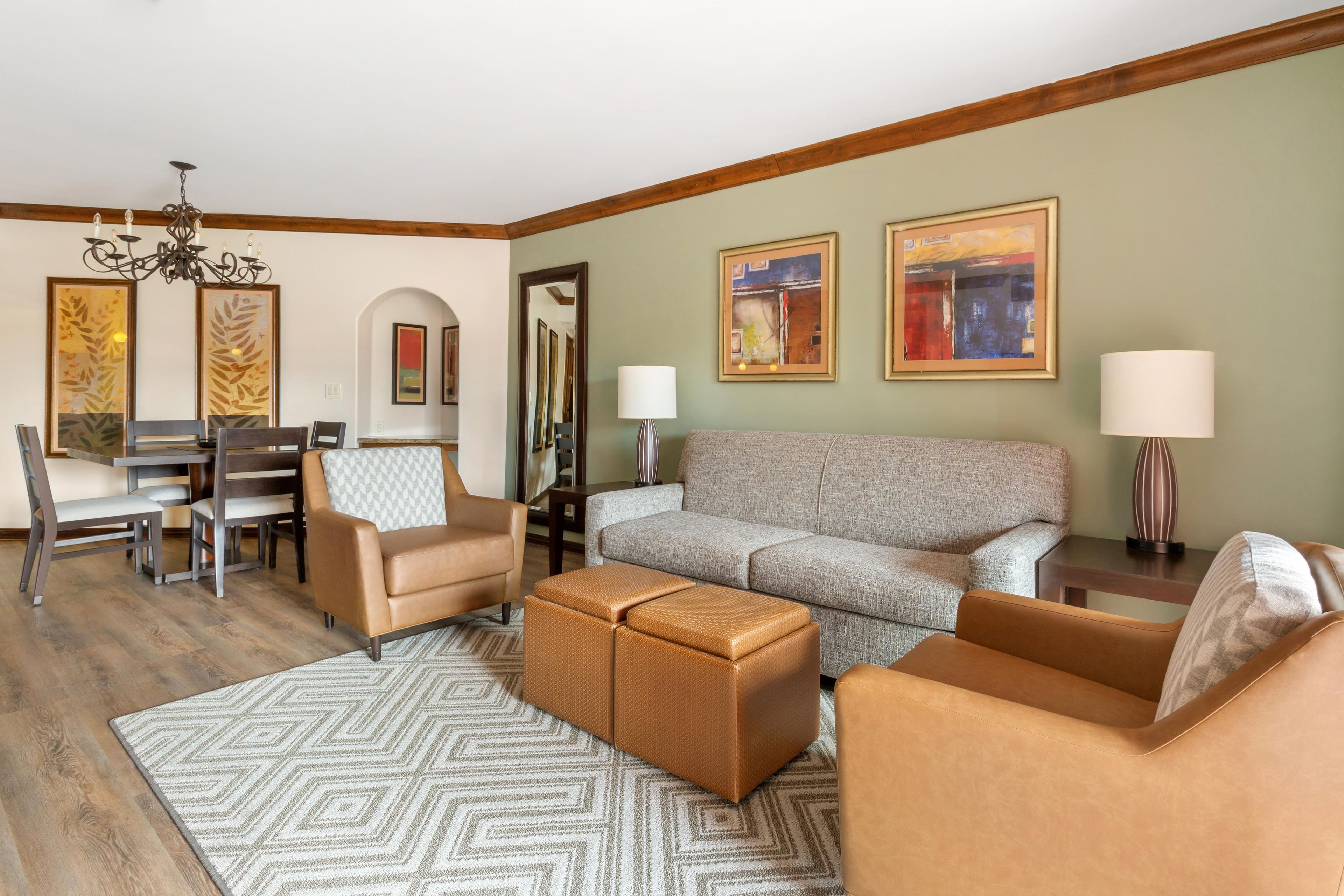 A living room with a sofa, chairs, a coffee table, a dining area with a table and chairs, and artwork on the walls.