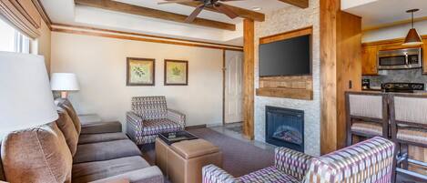 A living room with a fireplace, sofa, chairs, and a television.