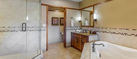 A bathroom with a glass shower enclosure, a vanity with a sink, and a bathtub.