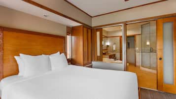 Une chambre d’hôtel avec un grand lit, une tête de lit en bois, une salle de bain avec une douche en verre et un miroir.