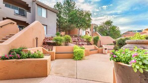 A courtyard with a central seating area, surrounded by planters with flowers and shrubs, and a staircase leading to an upper level. - Hilton Vacation Club Sedona Summit (Sedona)