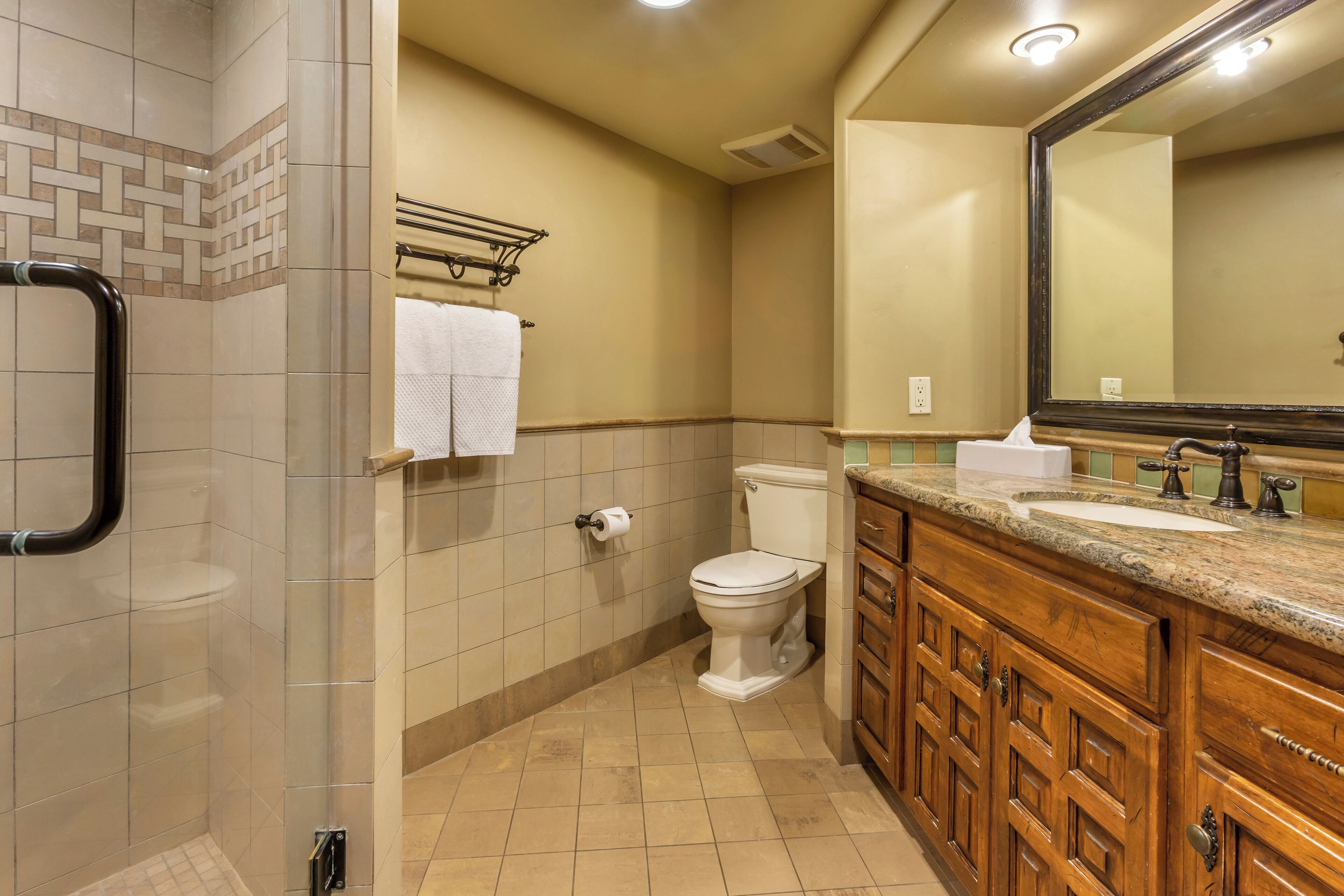 A bathroom with a shower, toilet, and vanity with a sink and mirror.