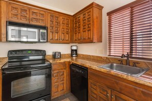 A kitchen with wooden cabinets, a stainless steel microwave, a black stove, a dishwasher, a coffee maker, and a sink. - Hilton Vacation Club Sedona Summit (Sedona)