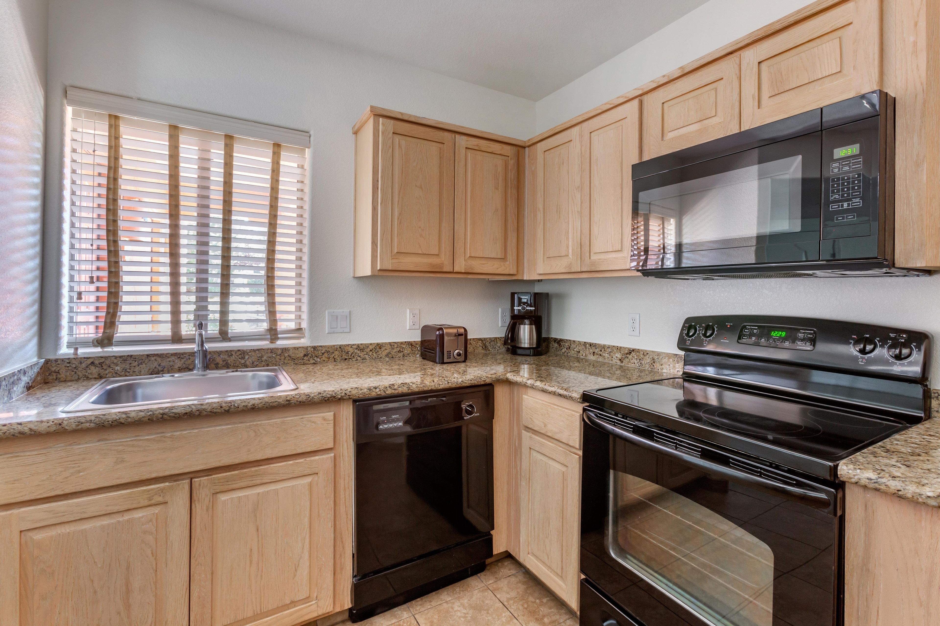 A kitchen with wooden cabinets, a stainless steel sink, a toaster, a coffee maker, and a stove.
