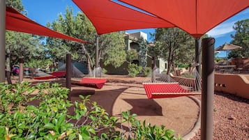 A patio area with red canopies, hammocks, and a small pool.