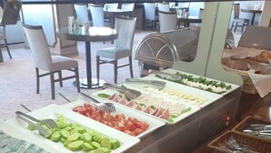 A buffet with various food options including sliced cucumbers, tomatoes, and meats.