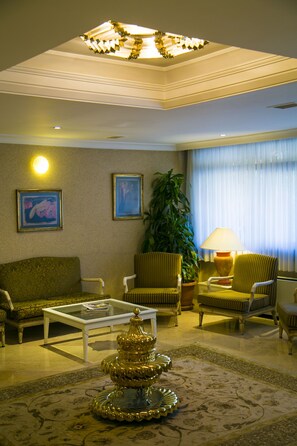 A living room with a sofa, armchairs, a coffee table, a decorative fountain, and a large plant. - Apart Hotel Best (Ankara)