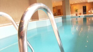 A swimming pool with clear blue water and metal pool ladders.