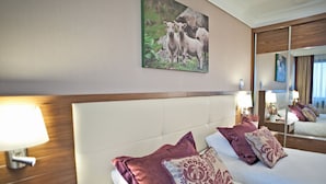 A hotel room with two beds, a large mirror, and a painting of sheep on the wall.