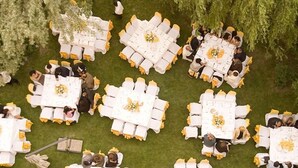 An outdoor event with round tables arranged in a circular pattern, surrounded by guests.
