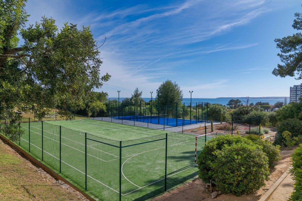 A tennis court surrounded by trees and a clear sky.