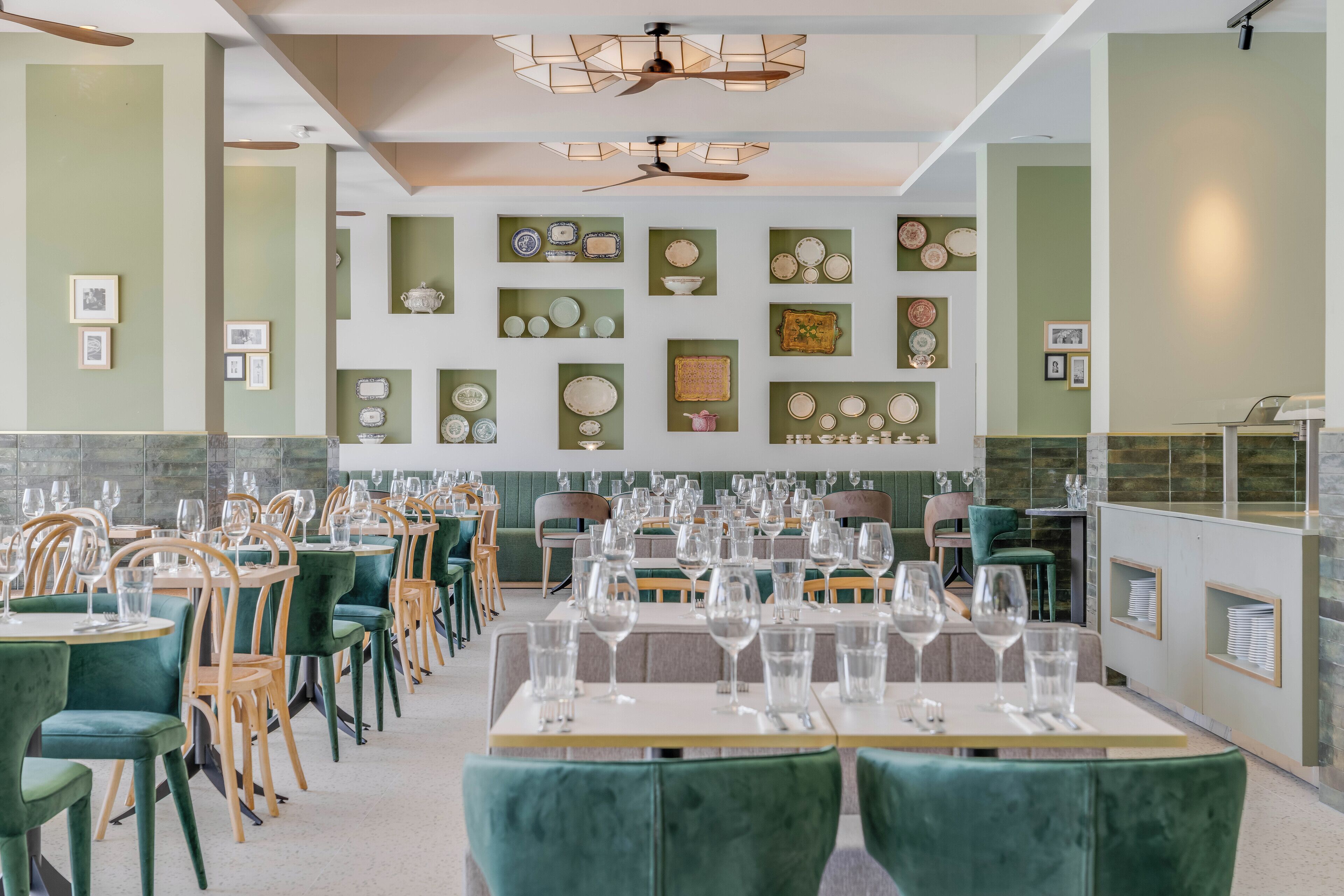 A restaurant with green walls, multiple dining tables, and chairs.
