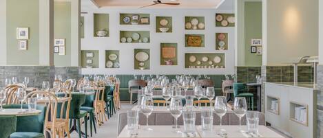 A restaurant with green walls, multiple dining tables, and chairs.