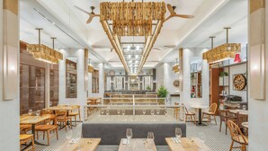 A modern restaurant interior with wooden tables, grey booths, and a central seating area. - Pestana Blue Alvor Beach - All Inclusive Hotel (Portimão)