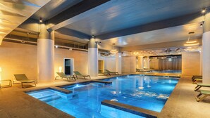 An indoor swimming pool with multiple lanes, lounge chairs, and a sauna area. - Pestana Blue Alvor Beach - All Inclusive Hotel (Portimão)