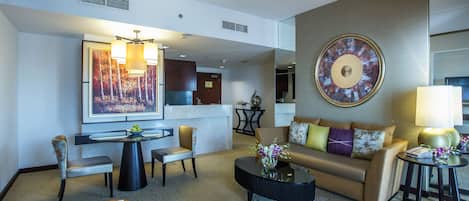 A modern hotel lobby with a sofa, chairs, a coffee table, and a dining area.