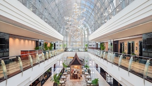 A multi-level atrium with a glass ceiling, a central seating area, and a modern design.