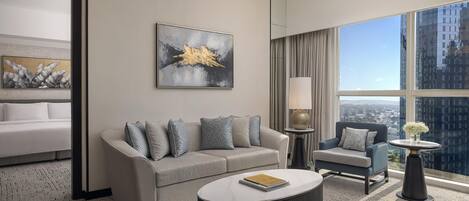 A modern hotel room with a sofa, armchair, and a round coffee table.