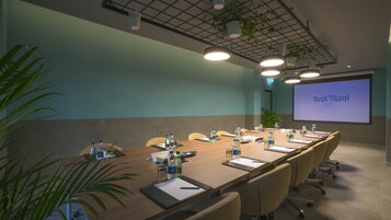 Une salle de conférence avec une longue table, des chaises, des bouteilles d’eau et un écran de projection affichant le texte « Duisit Thani Dubai ».