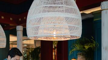 A restaurant with round tables, wicker lamps, and a red and blue color scheme.