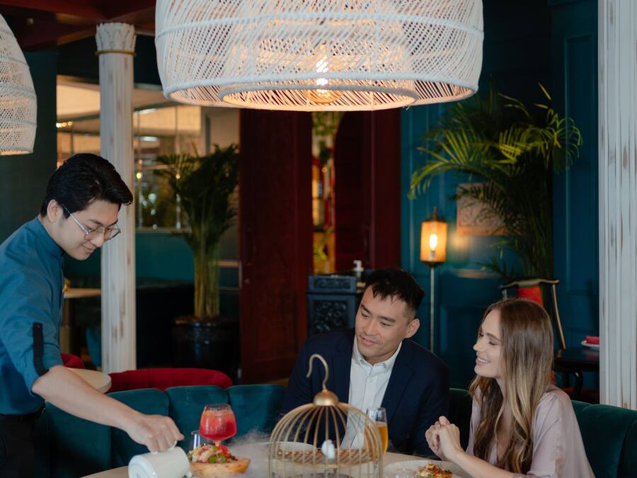 A restaurant with round tables, wicker lamps, and a red and blue color scheme.