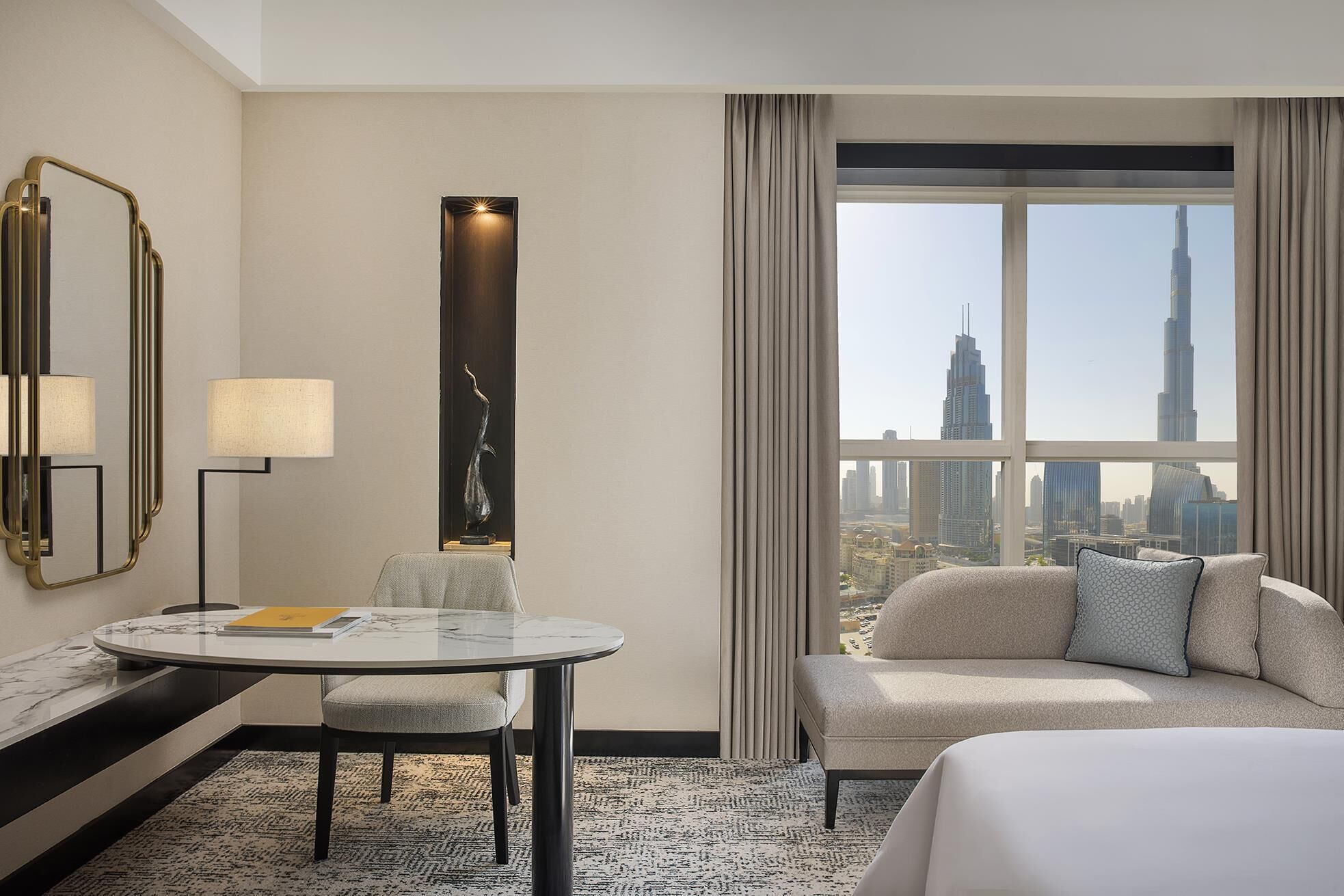 Ein Hotelzimmer mit Stadtblick, einem runden Tisch, einer Sitzecke und einer dekorativen Skulptur.