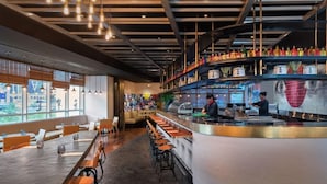 A modern restaurant interior with a bar area, seating, and a view through large windows. - Dusit Thani Dubai (Dubai)