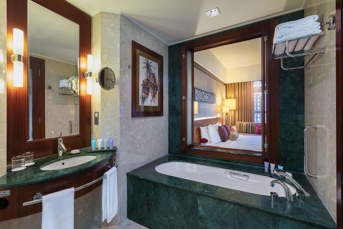 Ein modernes Badezimmer mit einem großen Spiegel, einer Badewanne und einem Waschtisch.