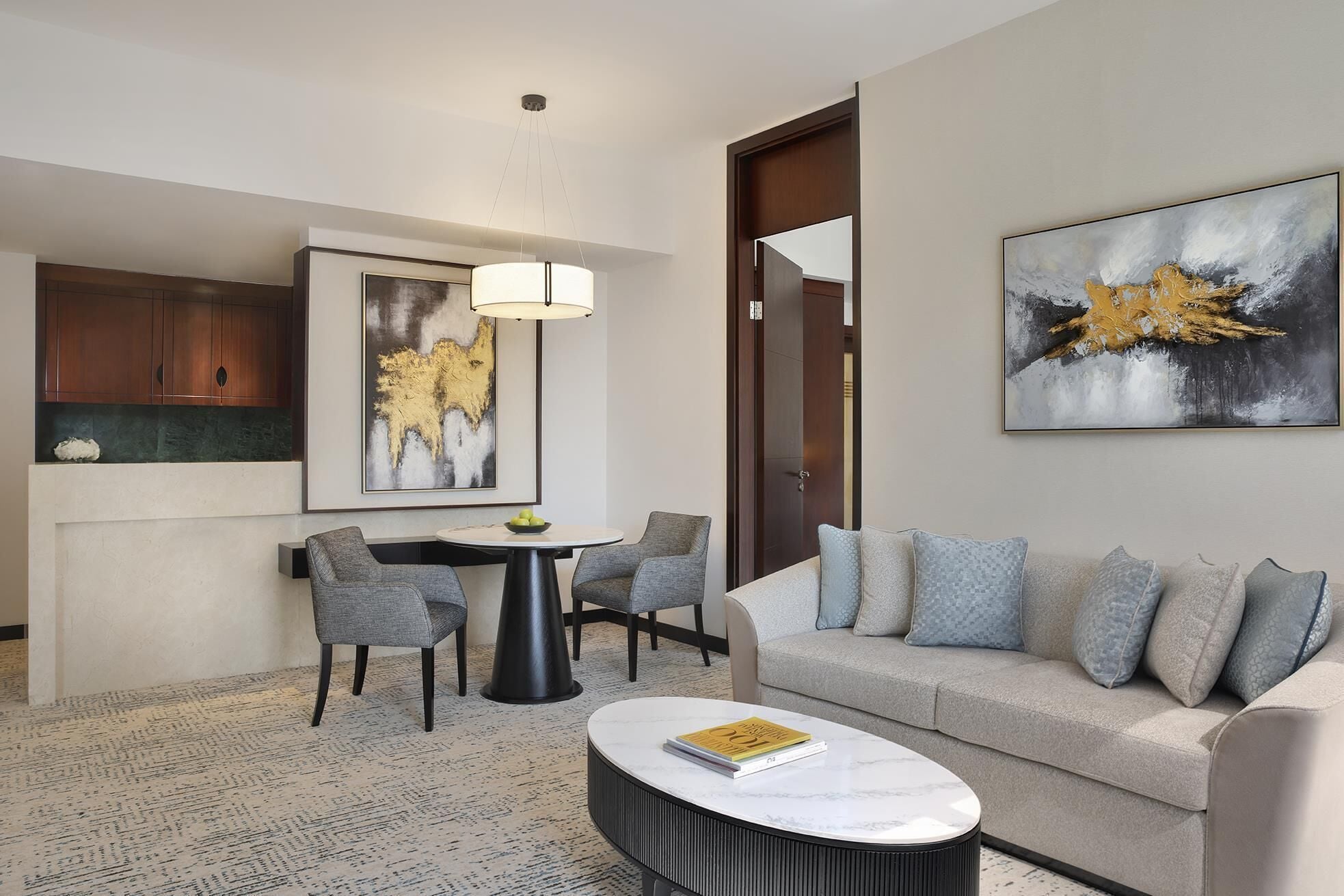 A modern living room with a round coffee table, grey sofa, and a dining area with chairs and a table.