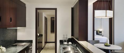 A modern kitchen with a built-in island, a dining area with a round table, and a separate bedroom with a large window.
