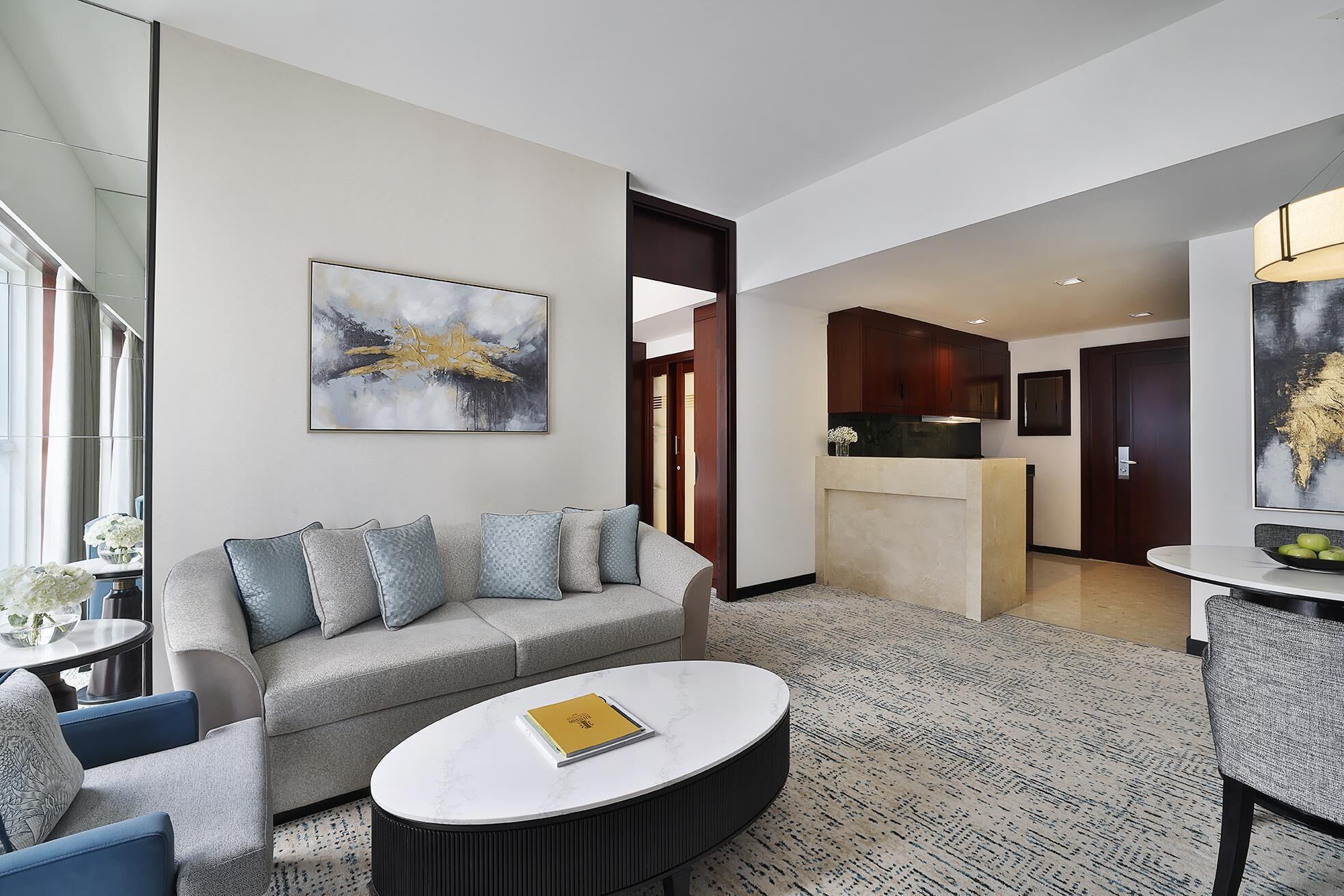 A modern living room with a grey sofa, a round coffee table, and a painting on the wall.