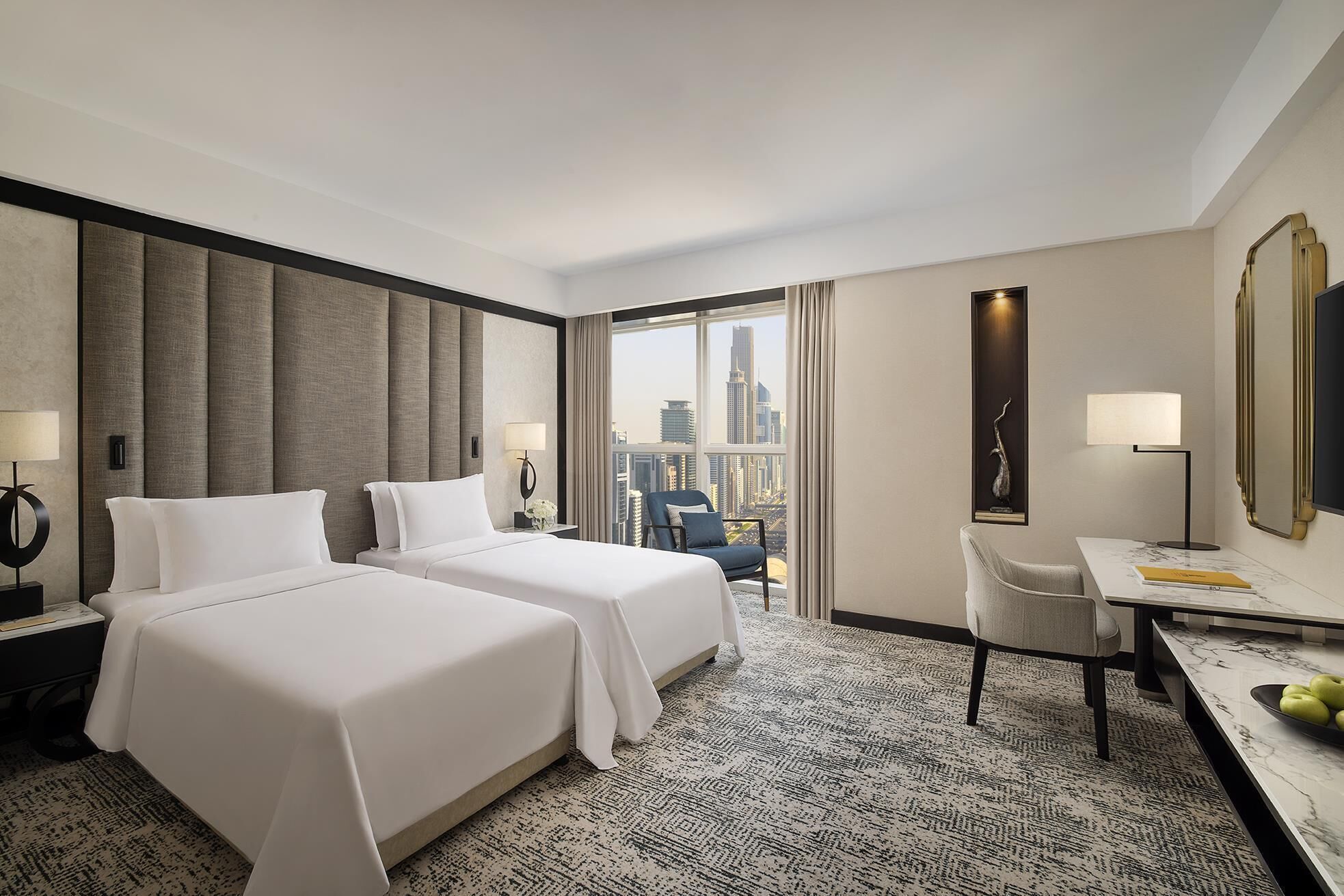 A hotel room with two beds, a desk, a chair, and a large window with a city view.