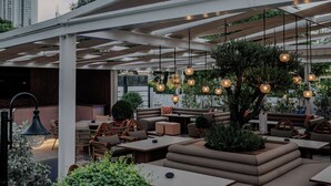 An outdoor seating area with modern furniture, hanging lights, and a view of the Burj Khalifa.