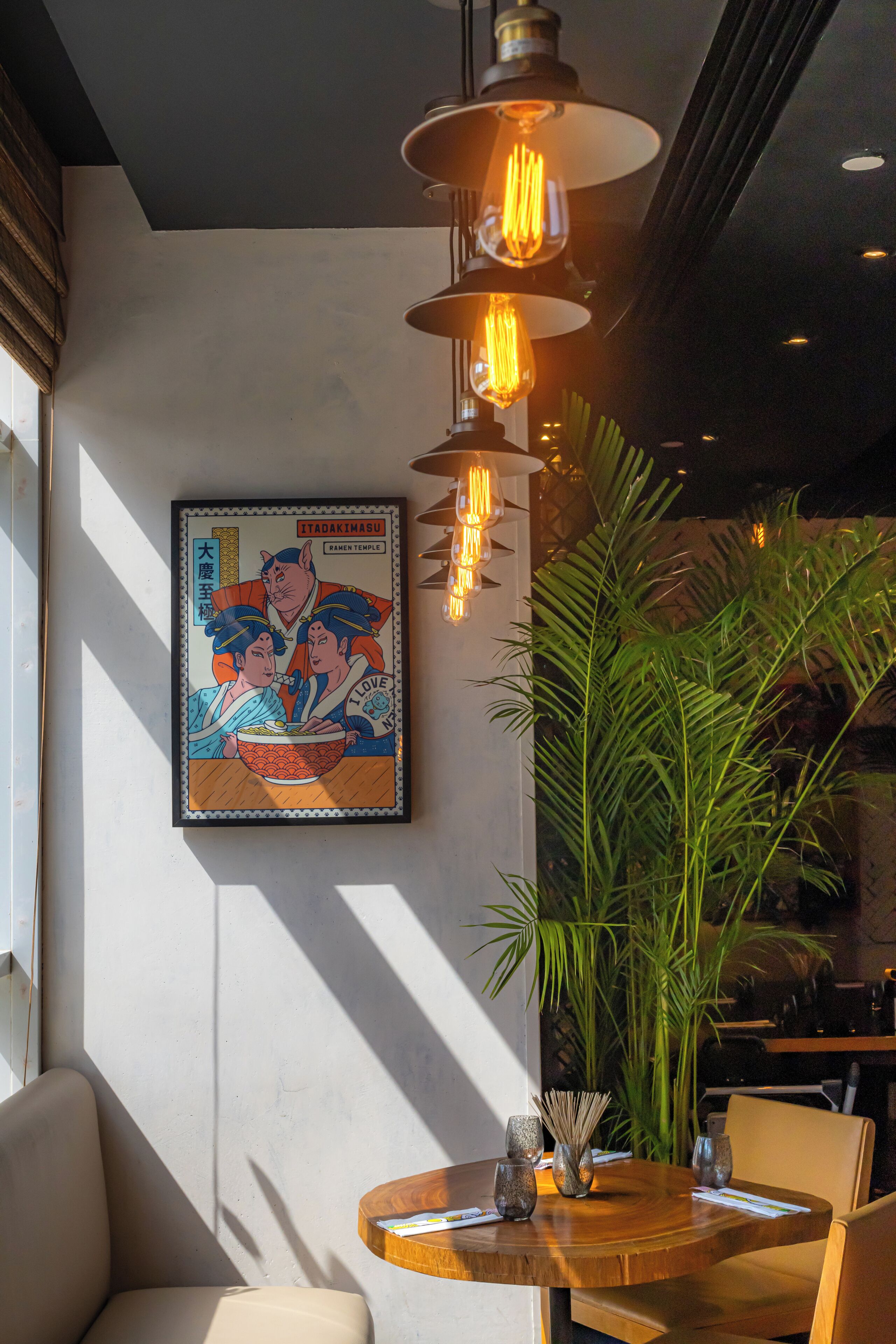 A dining area with a wooden table, chairs, and a large potted plant.