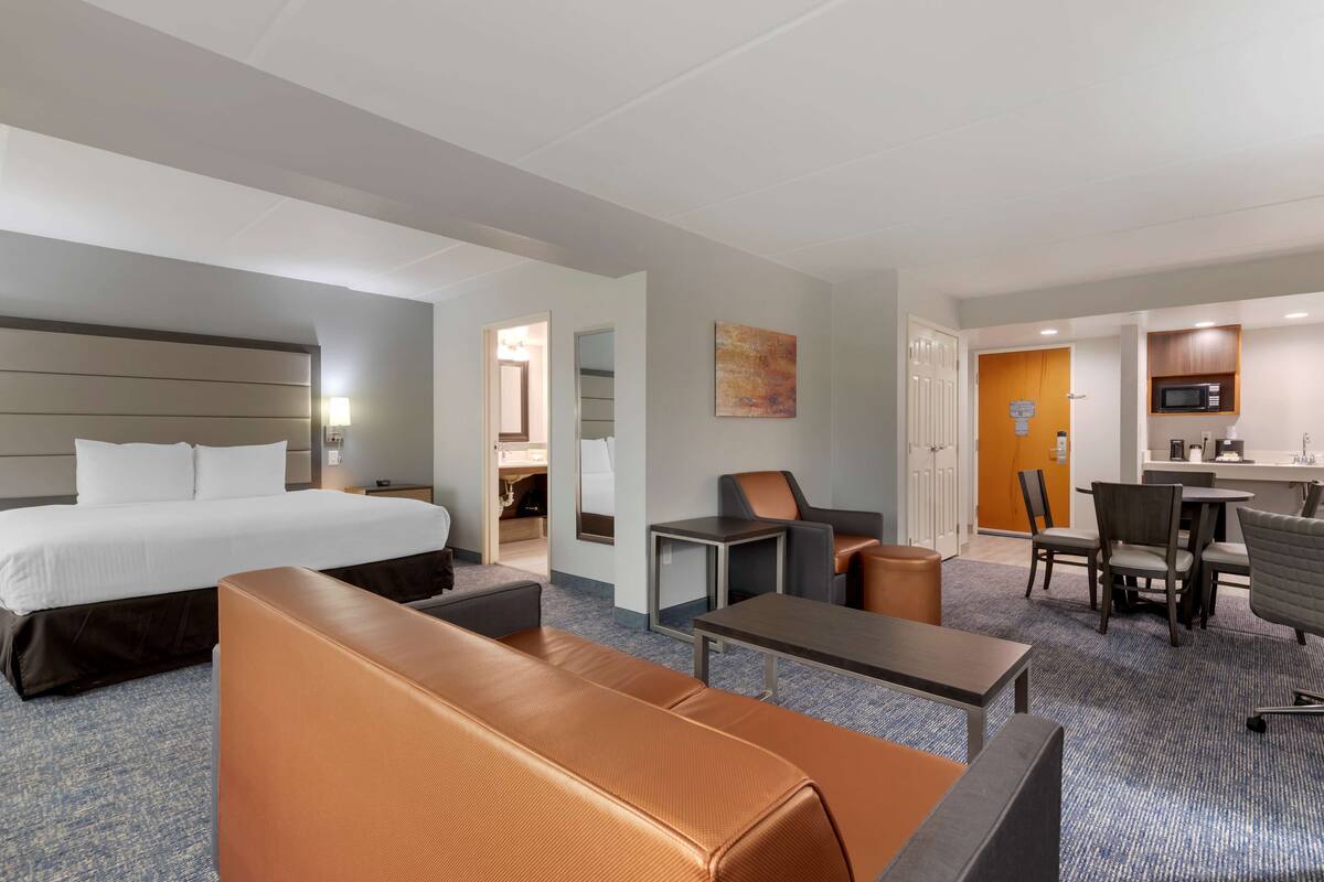Een hotelkamer met een groot bed, een bank, een bureau, een stoel en een kleine kitchenette.