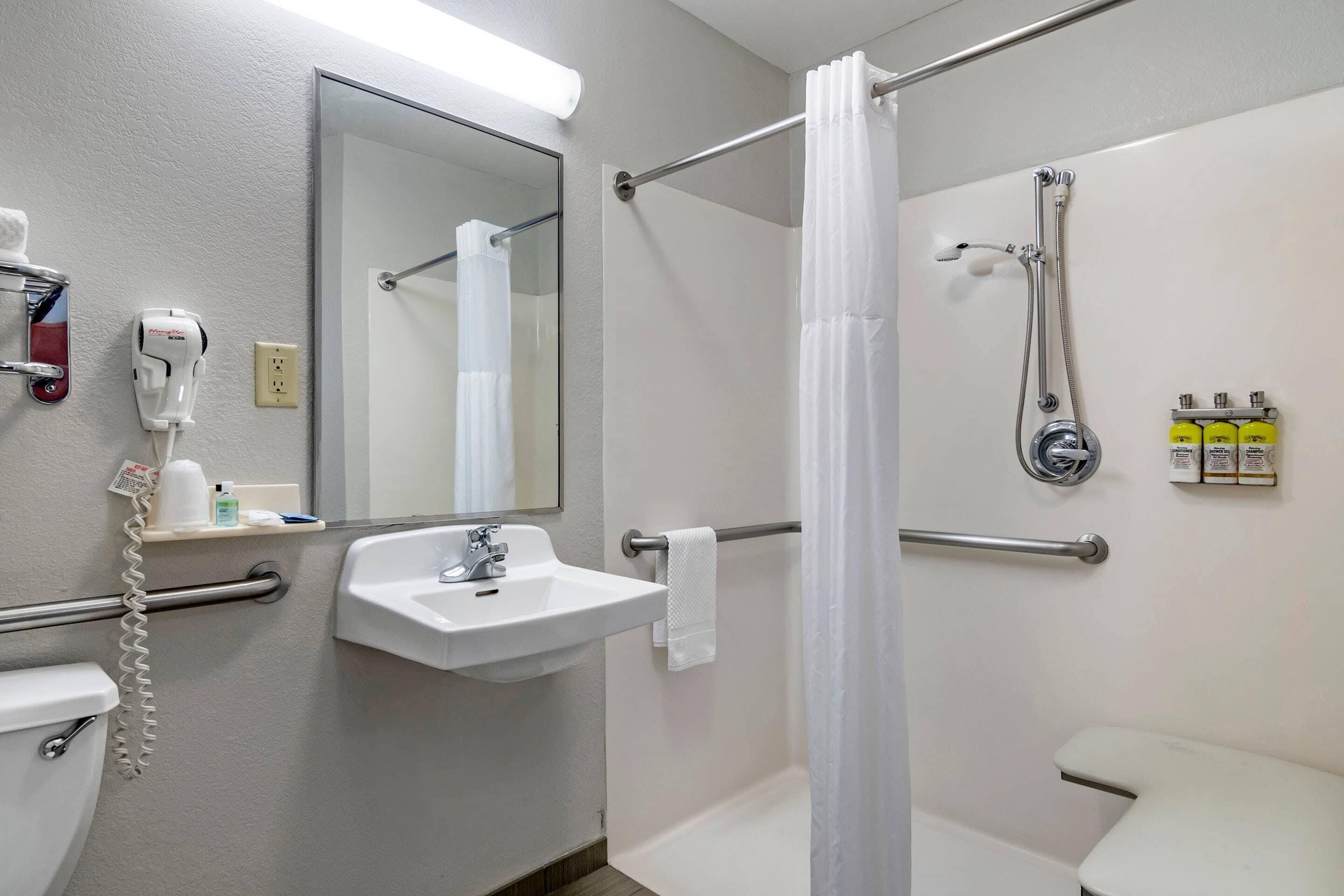 A bathroom with a sink, mirror, shower, and toilet.