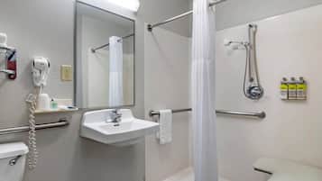 A bathroom with a sink, mirror, shower, and toilet.