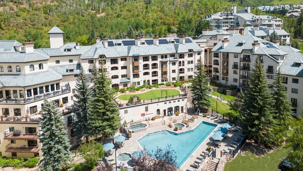 A resort with multiple buildings, a swimming pool, and surrounding greenery. - The Charter at Beaver Creek (Avon)