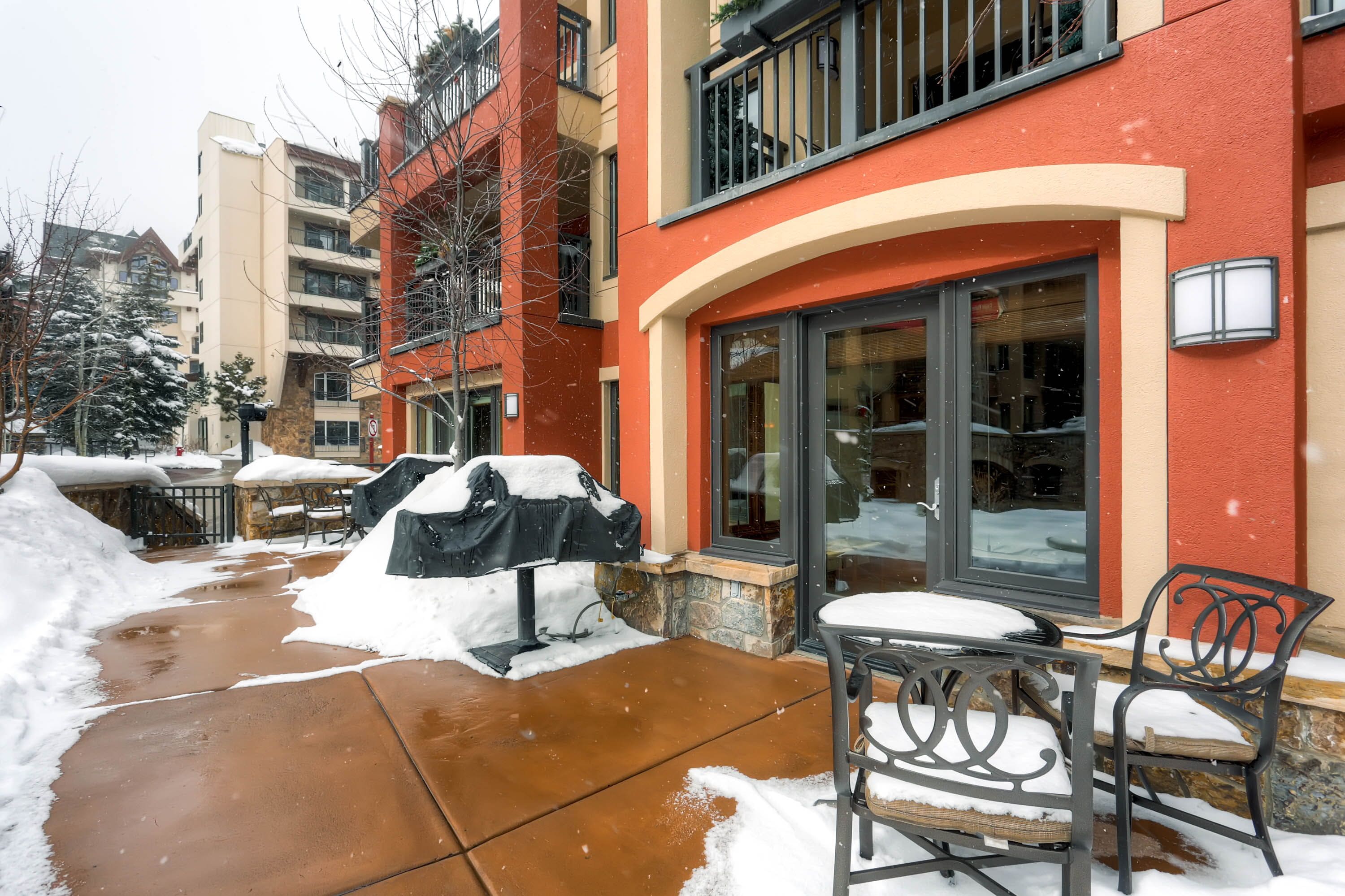 Een hotelgevel in het rood, een overdekt terras en sneeuw op de grond.