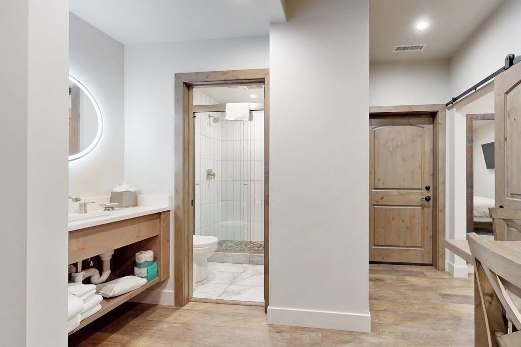 Une salle de bain moderne avec un meuble-lavabo en bois, un miroir rond et un espace douche.