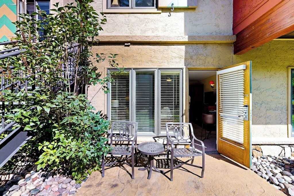 A patio with outdoor furniture, a stone pathway, and a building with a wooden door and windows.