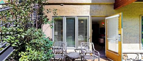 A patio with outdoor furniture, a stone pathway, and a building with a wooden door and windows.