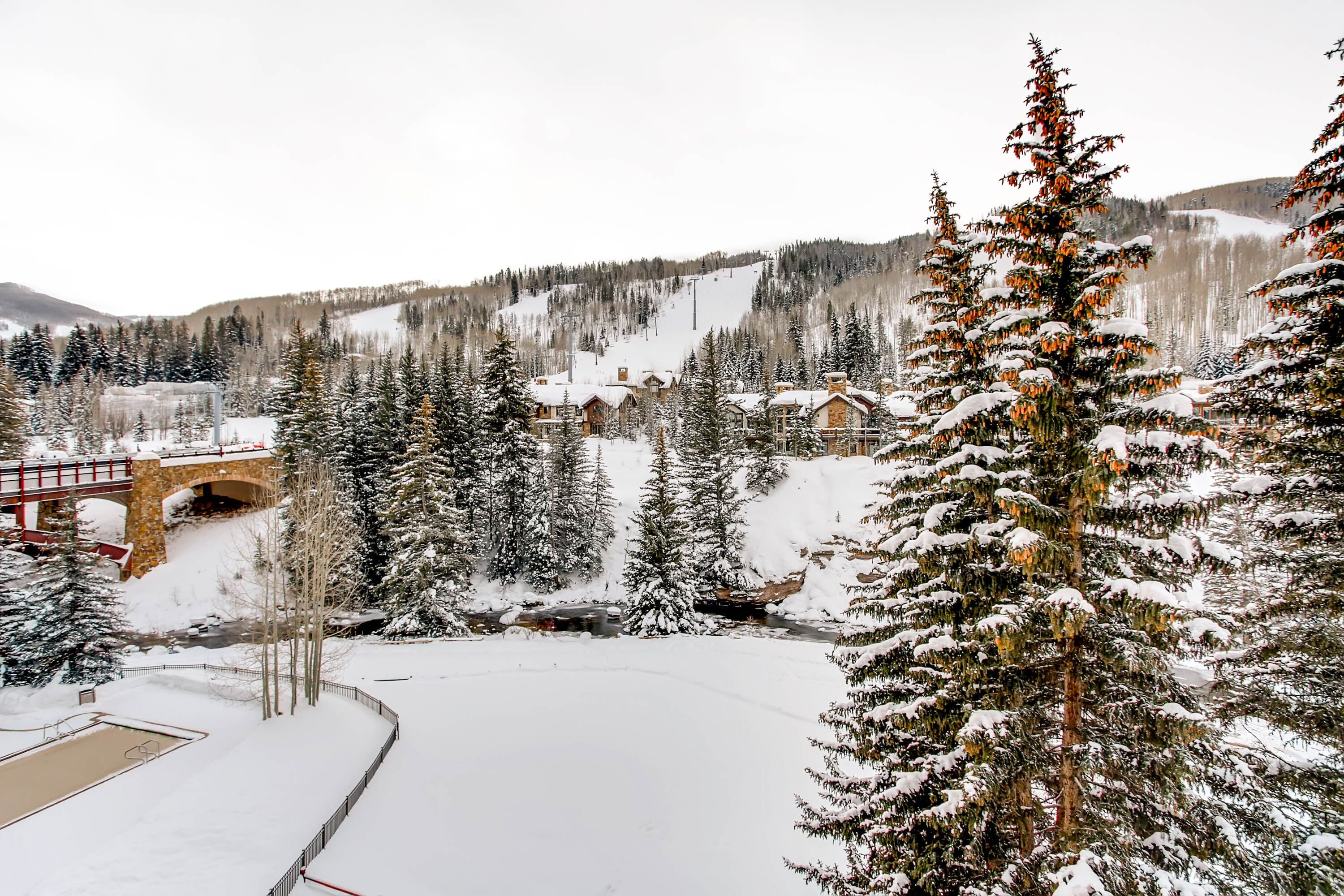 A snow-covered landscape with a ski resort, including a bridge, cabins, and a ski lift.
