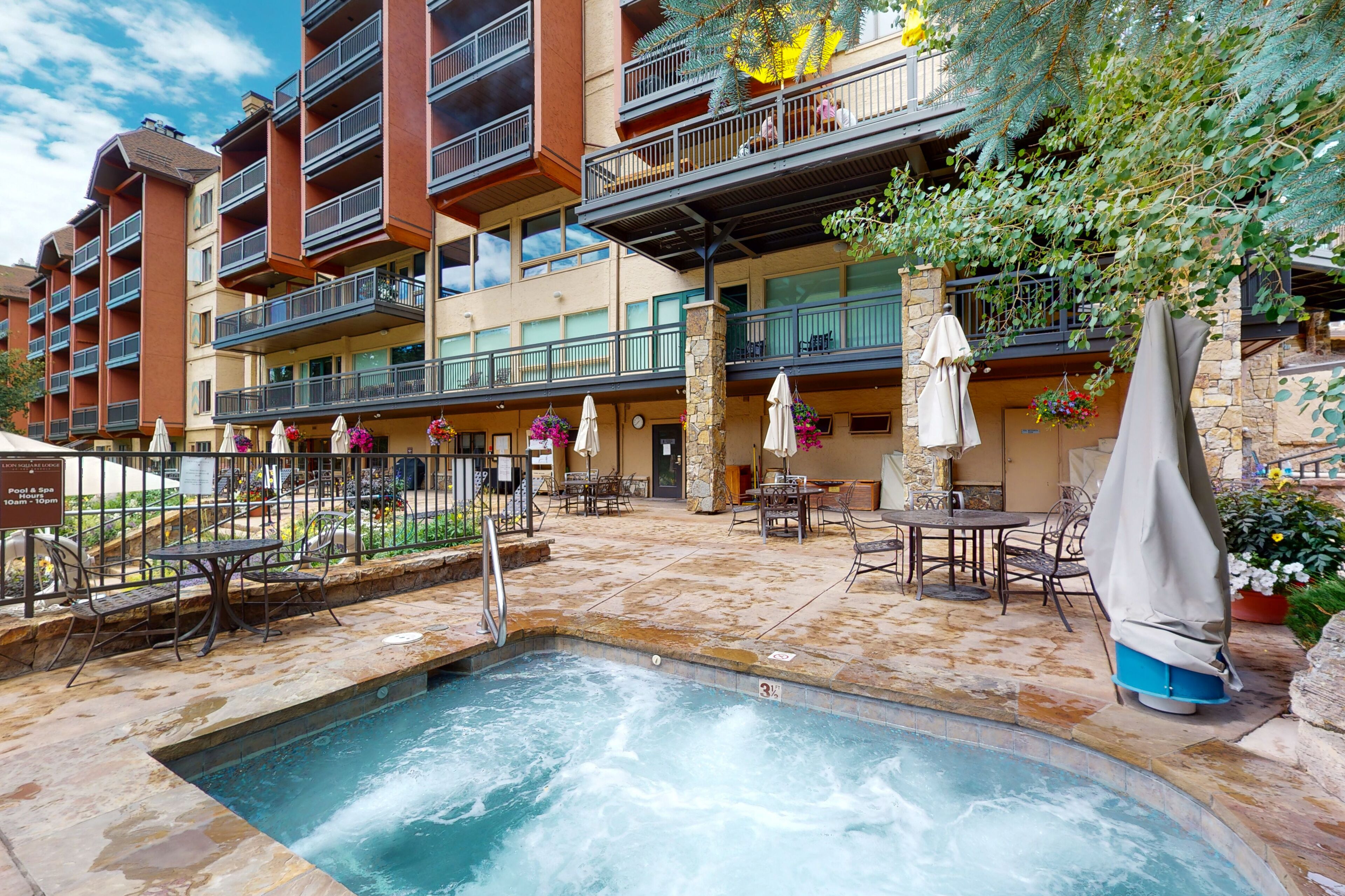 A hotel with outdoor hot tubs, patio furniture, and a pool area.